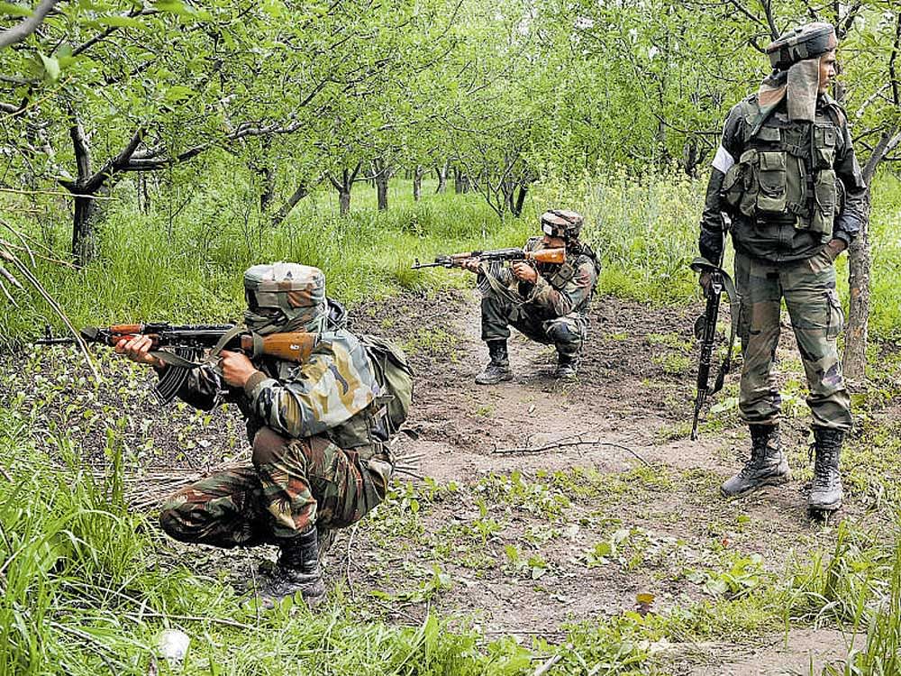 Armymen take position in an orchard during search operations at a village in Shopian district in J&K on Thursday. PTI