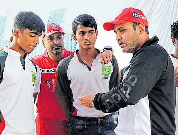 Kings XI Punjab'smentor Virender Sehwag passes on some batting tips as former Karnataka skipper J Arunkumar (in red) looks on in Bengaluru. DH PHOTO