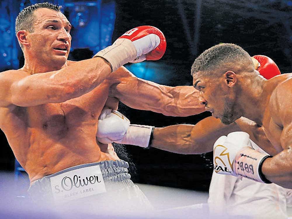 Anthony Joshua (right) staggers Wladimir Klitschko during their heavyweight title bout in London last Sunday. AFP