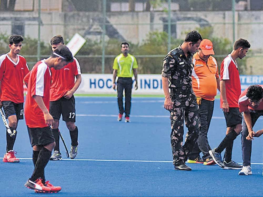 Lokesh Vats of Delhi Hockey writhes in pain after losing a tooth in a collision with Bajrang Sain of Madhya Pradesh Hockey during their 7th Hockey India Sub-junior Men's National Championship (Division A) match in Bengaluru on Wednesday.  In Picture: Vats' team-mates and officials search for the broken tooth. DH photo/ B H Shivakumar