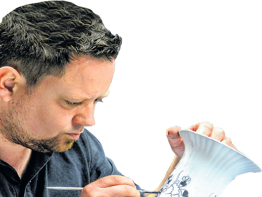 With Precision: An artist engaged in crafting Delft Blue
