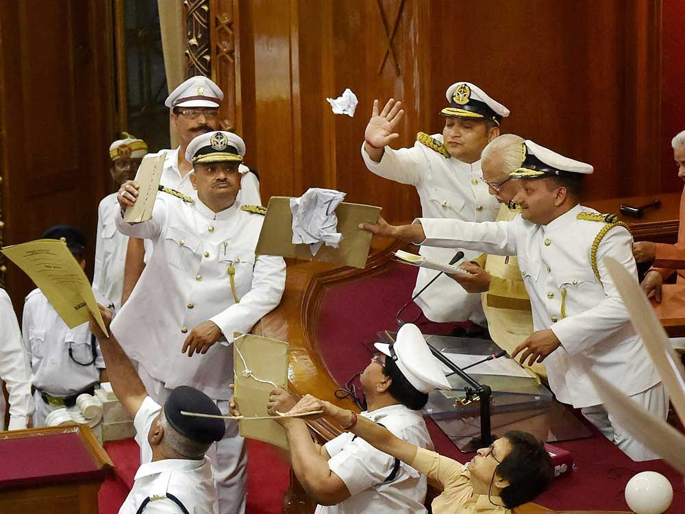 Marshals protecting UP Governor Ram Naik from paper balls thrown by agitating opposition MLAs during his address to the first sitting of the 17th Uttar Pradesh Assembly in Lucknow on Monday. The Assembly witnessed unruly scenes and pandemonium with the opposition disrupting proceedings over the issues including law and order situation in the state. PTI Photo