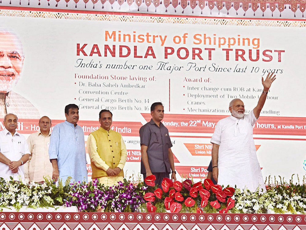 Prime Minister Narendra Modi waves at the unveiling of the digital plaque to mark the foundation stone laying of Development of 14th and 16th General Cargo Berth of Kandla Port, in Gandhidham, Gujarat on Monday. Union Minister for Road Transport & Highways and Shipping, Nitin Gadkari, the Chief Minister of Gujarat, Vijay Rupani, the Minister of State for Road Transport & Highways, Shipping and Chemicals & Fertilizers, Mansukh L. Mandaviya, the Minister of State for Road Transport & Highways and Shipping, P. Radhakrishnan are also seen. PTI Photo