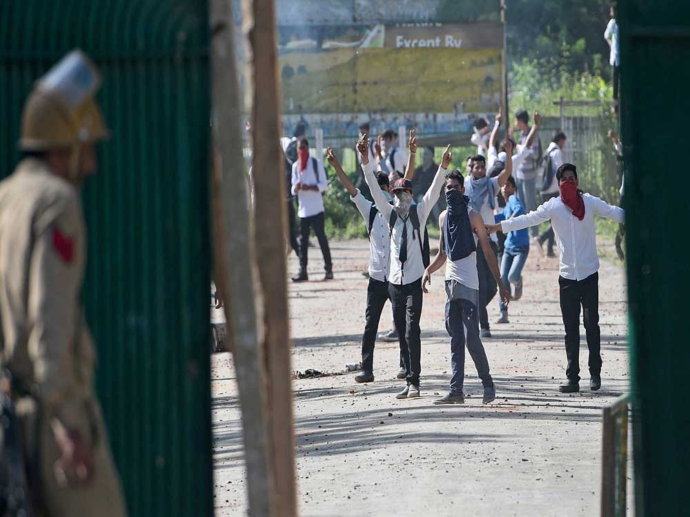 Students shout slogans while throwing stones on policemen during a clash at Govt Degree College Bemina in Srinagar. PTI Photo