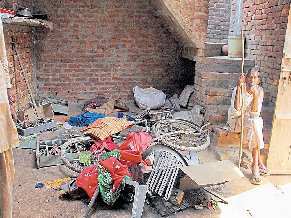 scene of disquiet: A man sitting near his damaged household in the violence-hit Shabbirpur village of Saharanpur district on Thursday. PTI