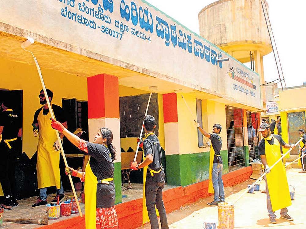 Volunteers paint the school building at Hegdenagar.
