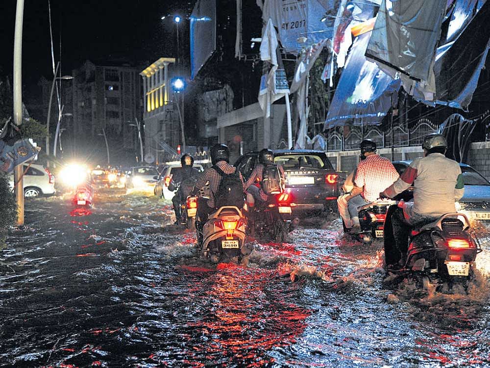 Motorists try to navigate the flooded road in front of UB City. DH photo