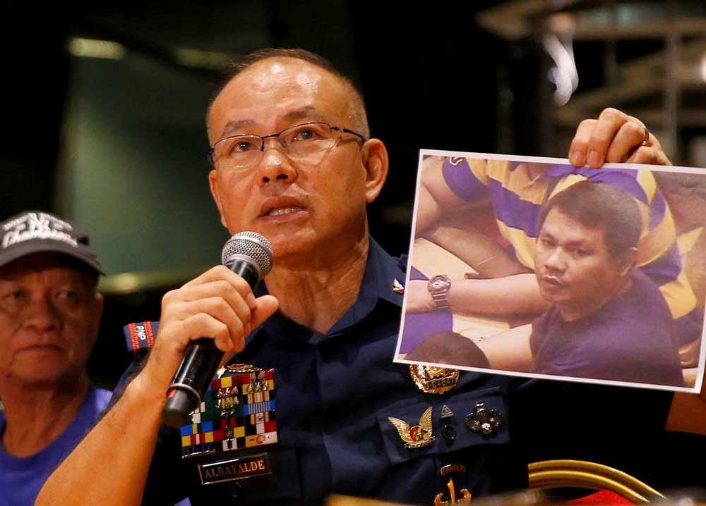 Police Gen. Oscar Albayalde holds a copy of an image of a gunman who stormed the Resorts World Manila complex whom he identified as Jessie Carlos during a news conference Sunday, June 4, 2017 in suburban Pasay city, southeast of Manila, Philippines. The lone suspect behind a deadly attack on the casino and shopping complex in Manila was a heavily indebted Filipino who was hooked on gambling, police said Sunday, bolstering their claim the assault was not terror-related. At left is the gunman's father Fernando Carlos. AP/PTI Photo