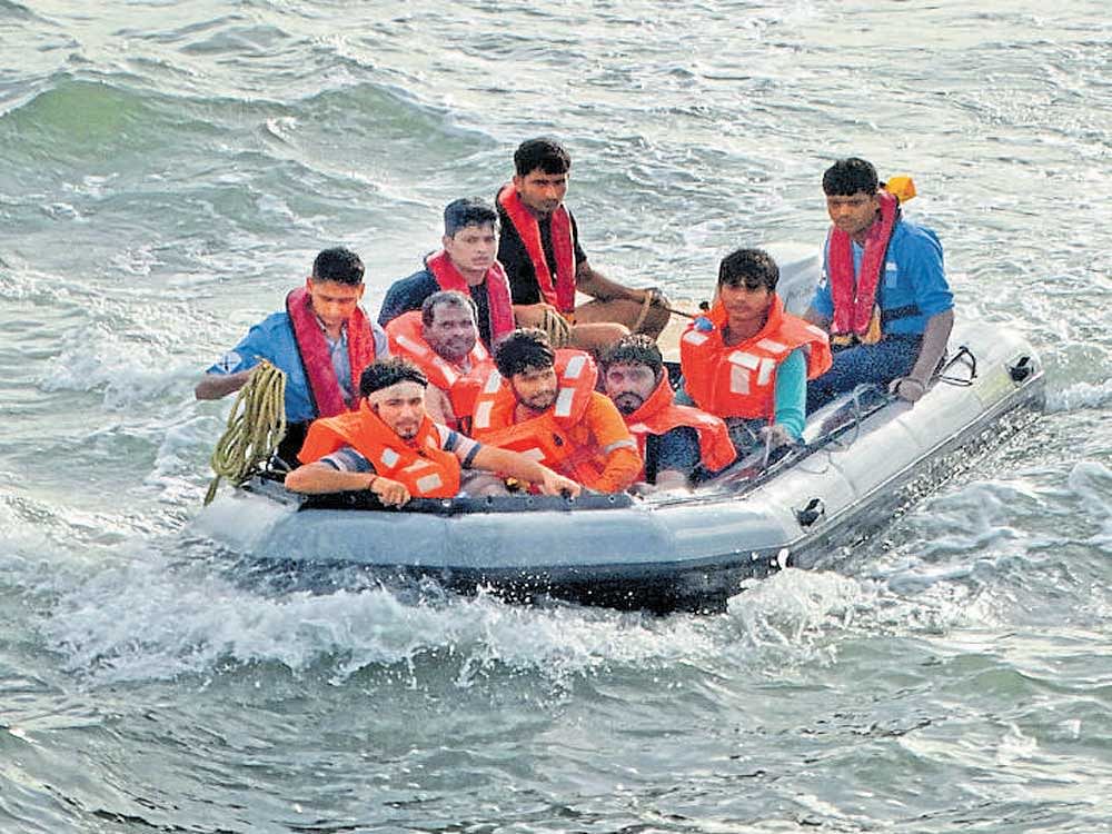 Workers rescued from the sinking barge in Arabian Sea are ferried in a dinghy towards the Indian Coast Guard Ship, near Ullal, Dakshina Kannada district, on Sunday. DH Photo
