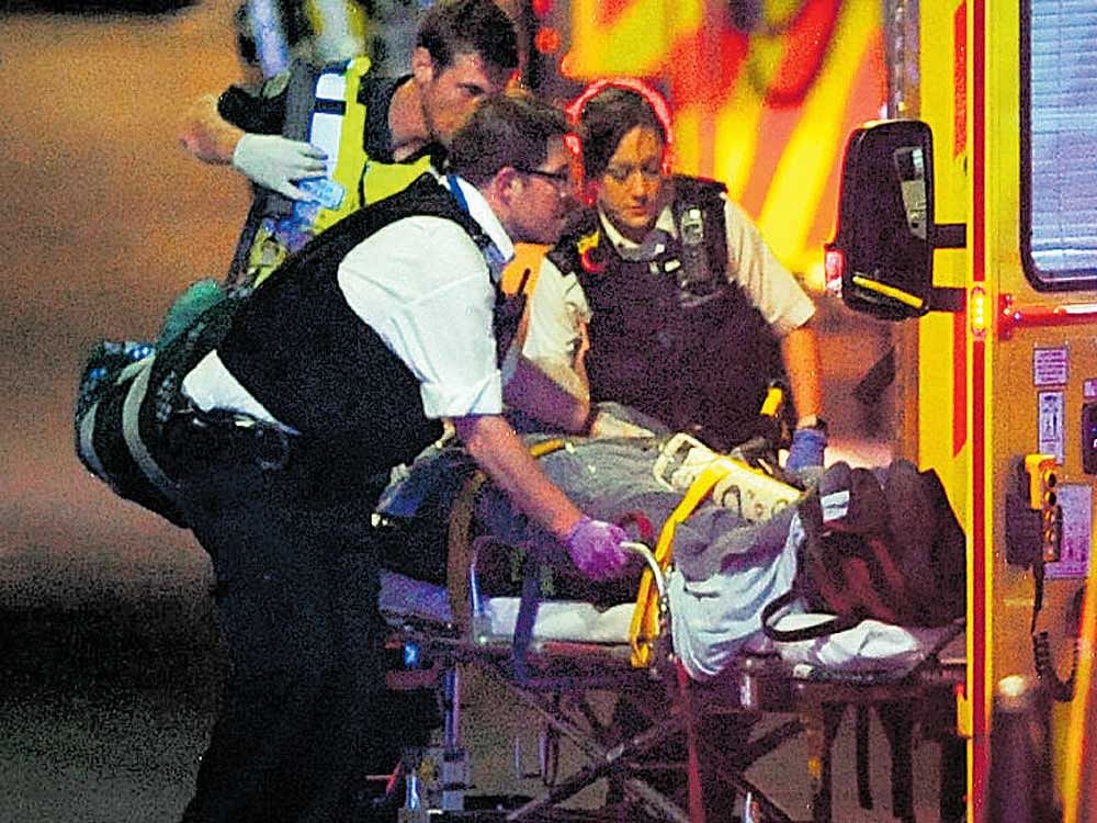 Police officers and members of the emergency services attend to a person injured in the terror attack on the London Bridge in central London on Sunday. afp