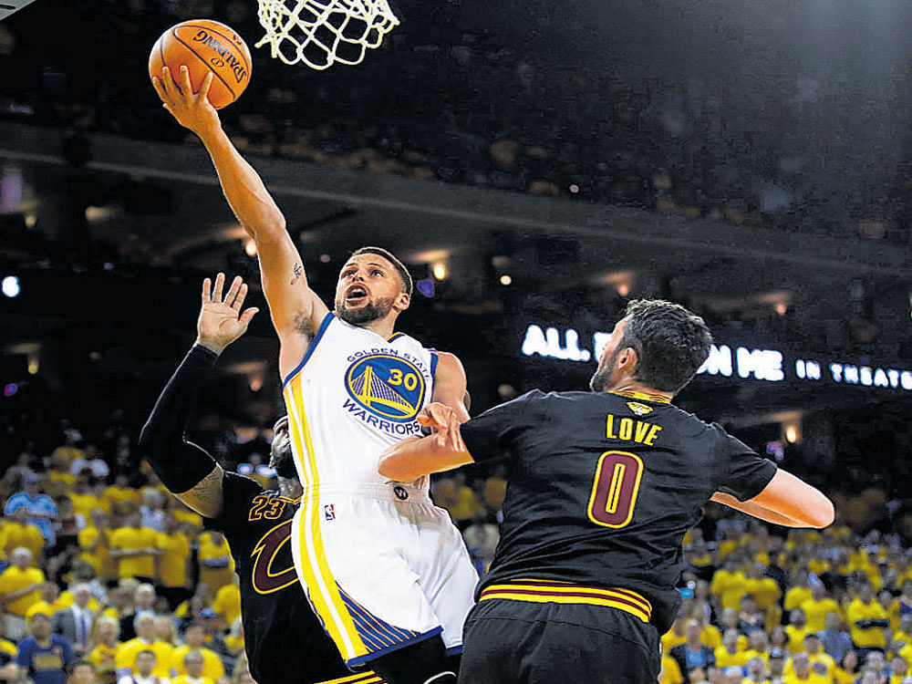 almost there Stephen Curry (centre) of the Golden State Warriors scores past the Cleveland Cavaliers defence. Reuters
