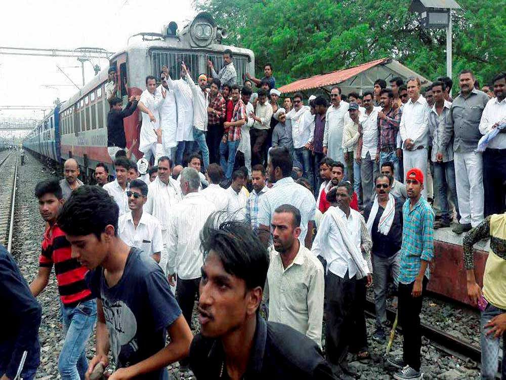 Farmers stopping a train during their nation-wide agitation in Dewas, Madhya Pradesh on Wednesday. PTI Photo