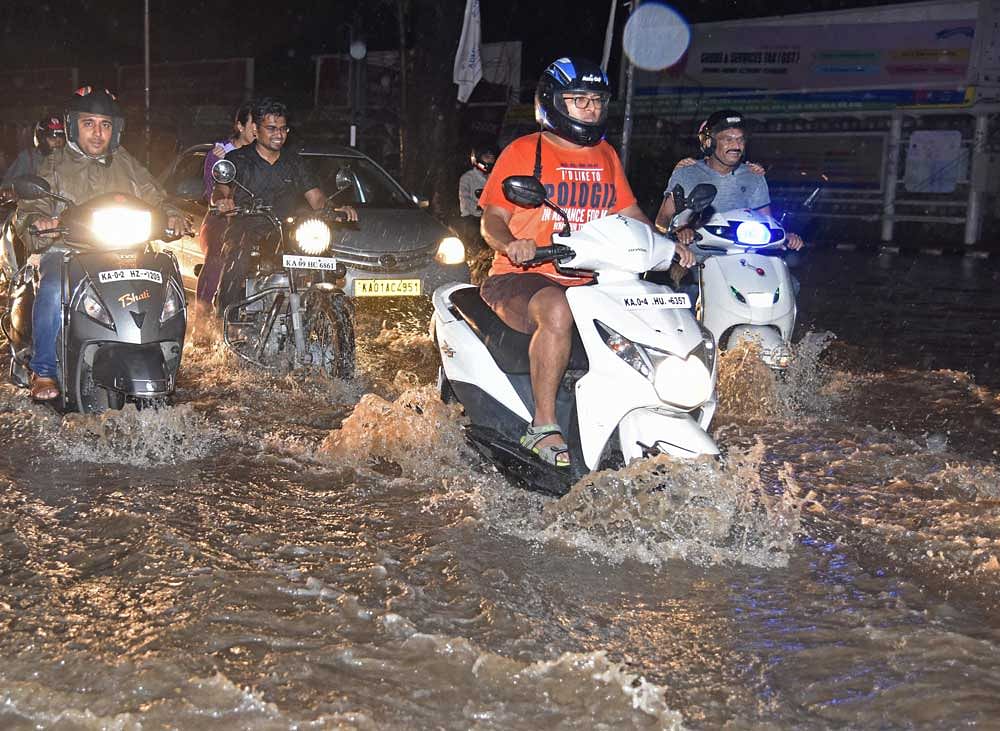 Riding a two-wheeler or driving a car gets extremely tricky, as potholes lurk under the sheets of water. DH Photo