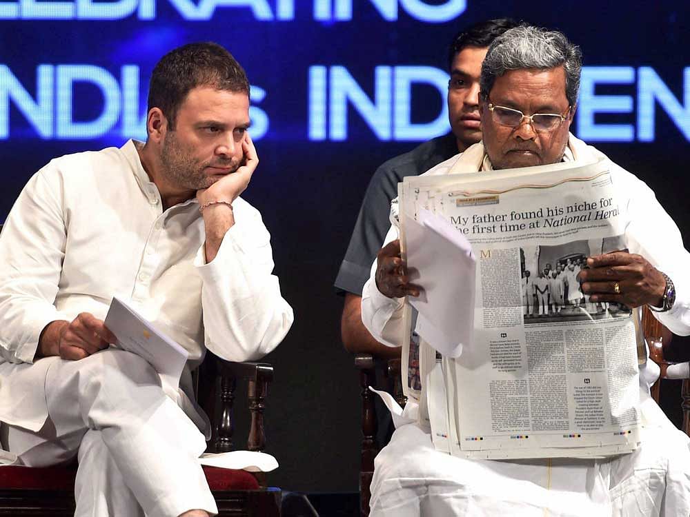 Congress Vice President Rahul Gandhi looks on as Karnataka Chief Minister Siddaramaiah goes through the commemorative edition of National Herald newspaper at its launch in Bengaluru on Monday. PTI photo.