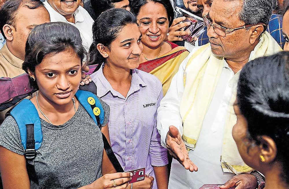 Chief Minister Siddaramiah interacts with students at the launch of BMTC smart cards at  Majestic bus stand on Saturday. Bengaluru Metropolitan Transport Corporation (BMTC)  Managing Director Dr Ekroop Caur is seen. DH photo