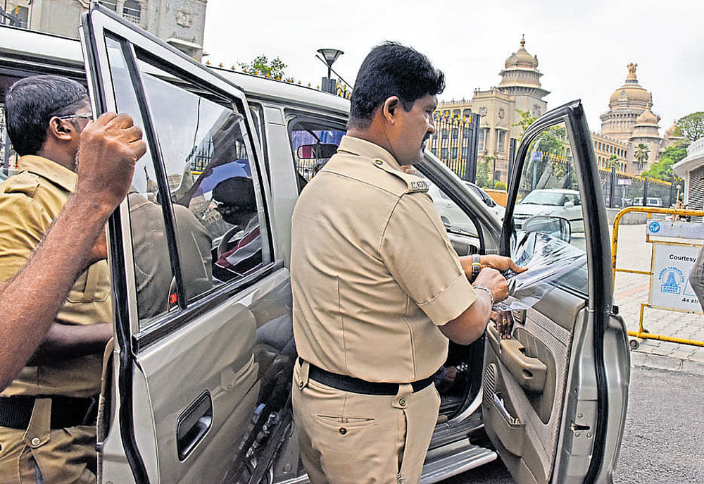 Transport officials remove tinted sheets from vehicles at the Vidhana Soudha in Bengaluru on Monday for violating the motor vehicle Rules. dh Photo