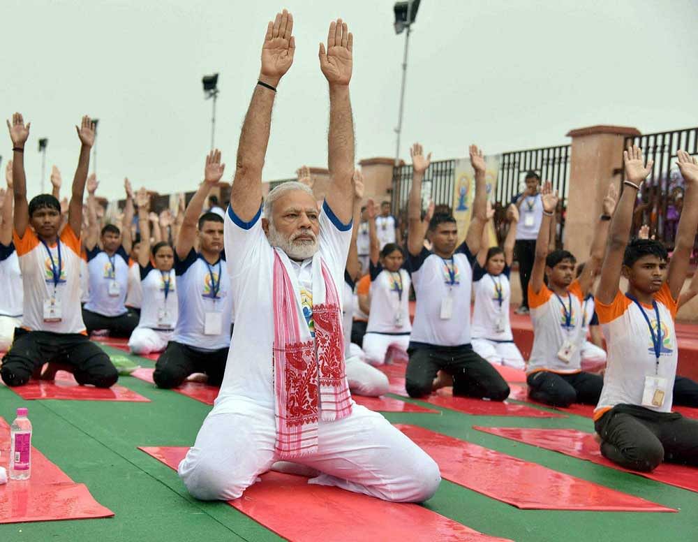 Prime Minister Narendra Modi performs yoga along with thousands of others during a mass yoga event on 3rd International Yoga Day in Lucknow, on Wednesday. PTI Photo/PIB