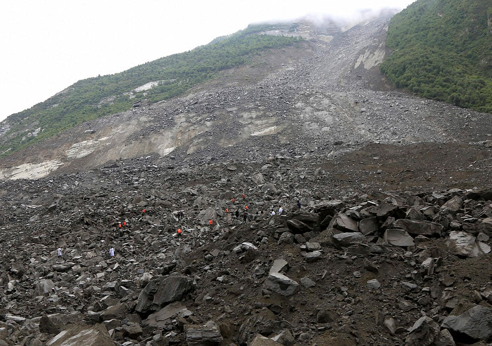 Workers attempt to clear out debris from an area in Sichuan following a landslide which has left around 100 buried. Photo credit: AP.