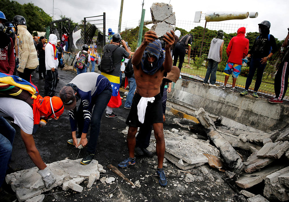 Protesters break pieces of stone to filing at security forces near an Air Force base in their protest against Maduro. Photo credit: reuters.