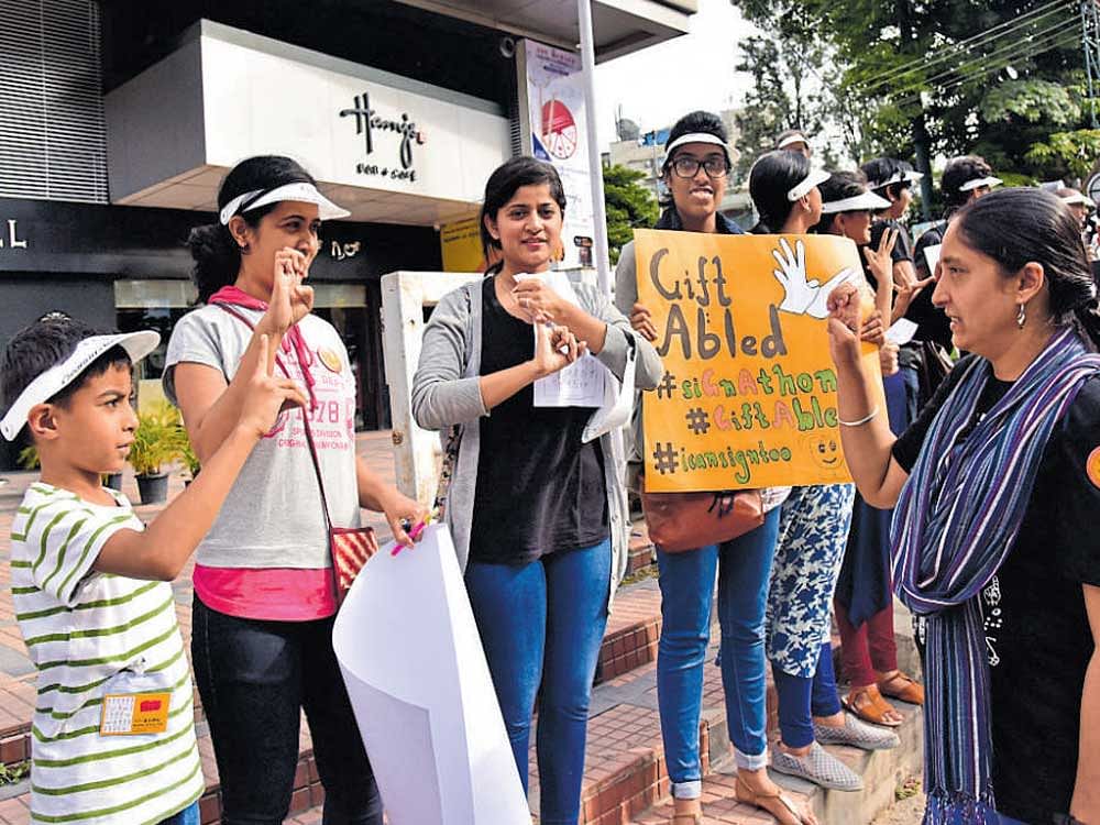 Volunteers take part in 'siGnAthon - a silent human chain,' to create awareness on the needs of the disabled and to teach people sign language to mark the birth anniversary of Helen Keller at Koramangala on Sunday. dh photo