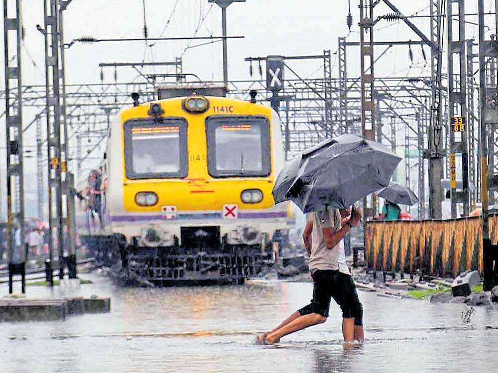 Boys cross waterlogged railway tracks after heavy rain in Thane, Mumbai, on Sunday. PTI