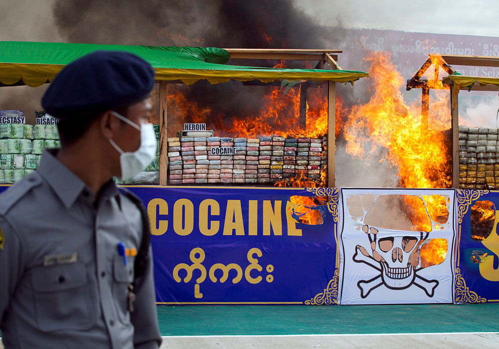 A security personnel looks on as a stack of illegal drugs is set alight in Yangon, Myanmar. Photo credit: AP.