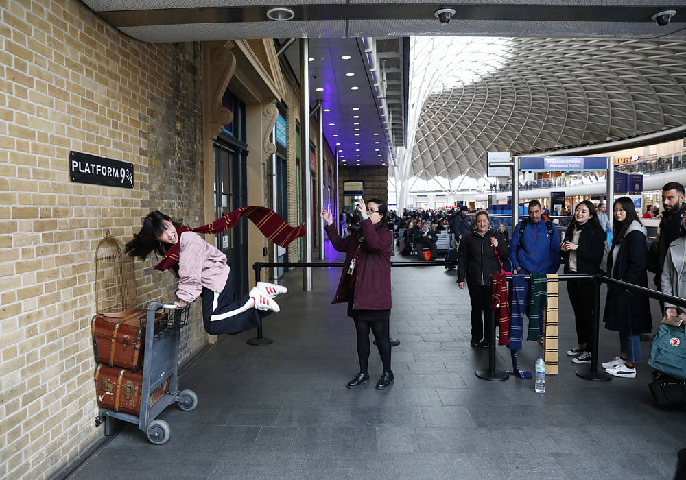 A Harry Potter fan poses in front of Platform 9 and 3/4 in Kings Cross station. Photo credit: reuters.