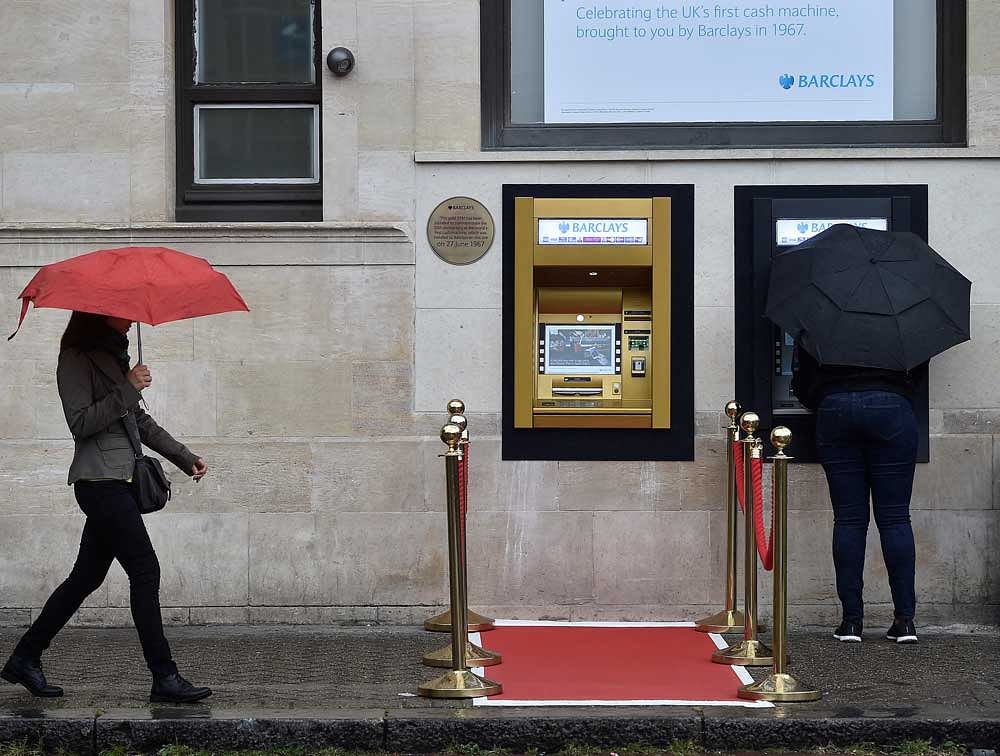 A woman uses a golden ATM, marking the location of the first 'hole in the wall,' which opened fifty years ago, in Enfield, Britain June 27, 2017. REUTERS
