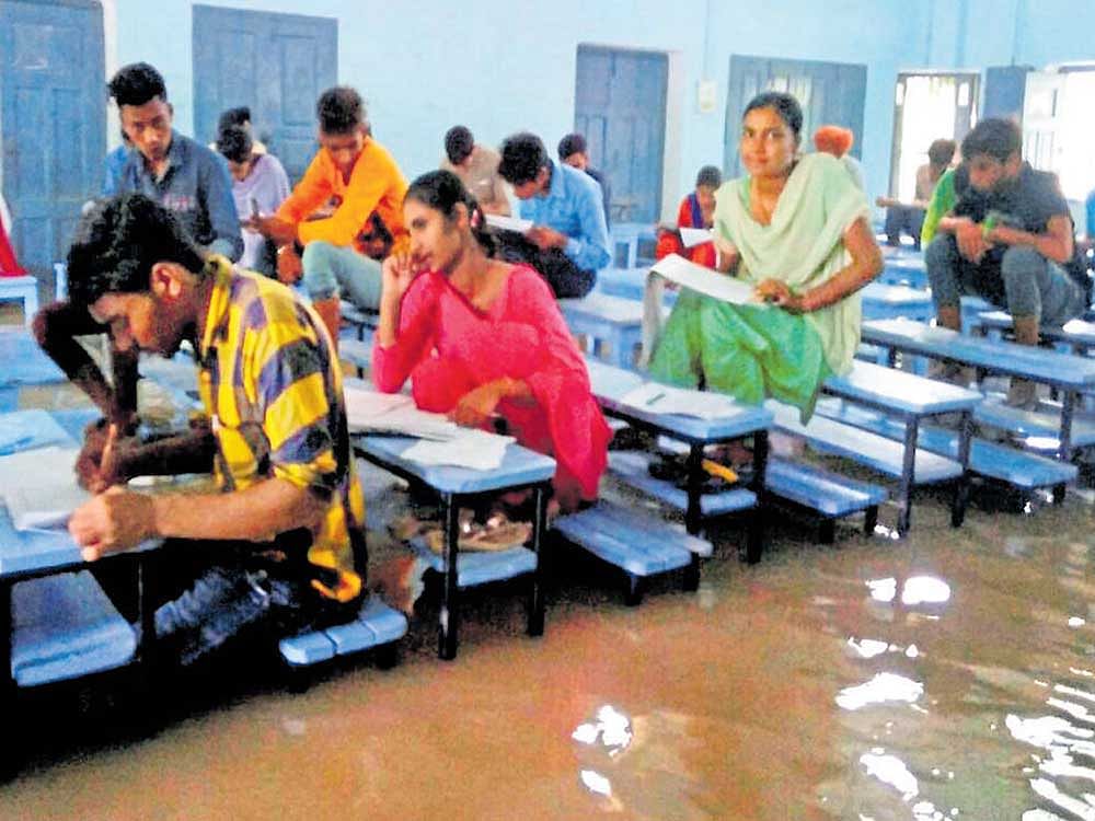 Testing times: Students write an examination in a flooded hall after heavy downpour in Mansa, Punjab, on Friday. PTI