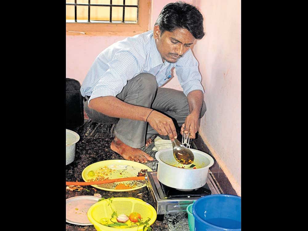 Mechanical engineer Shivanand Kalabanura cooks a puffed rice dish during the practical exam for the post of cooks in BCM&#8200;hostels in Bagalkot on Monday. DH Photo
