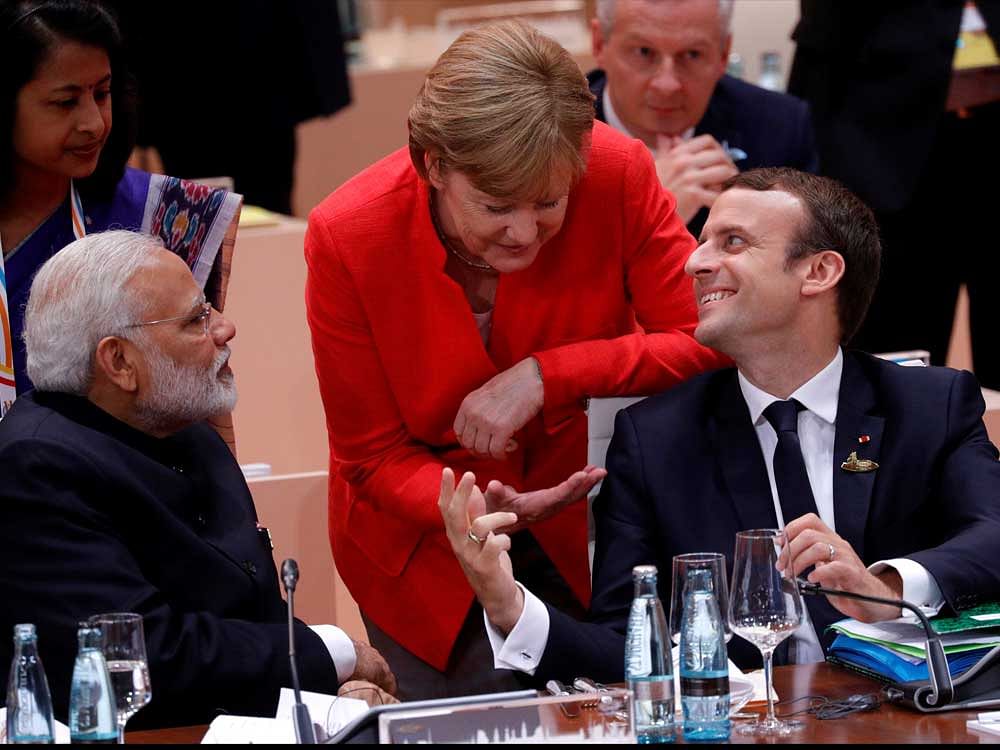 French President Emmanuel Macron talks to German Chancellor Angela Merkel as India's Prime Minister Narendra Modi listens during the G20 leaders summit in Hamburg, Germany July 7, 2017. REUTERS
