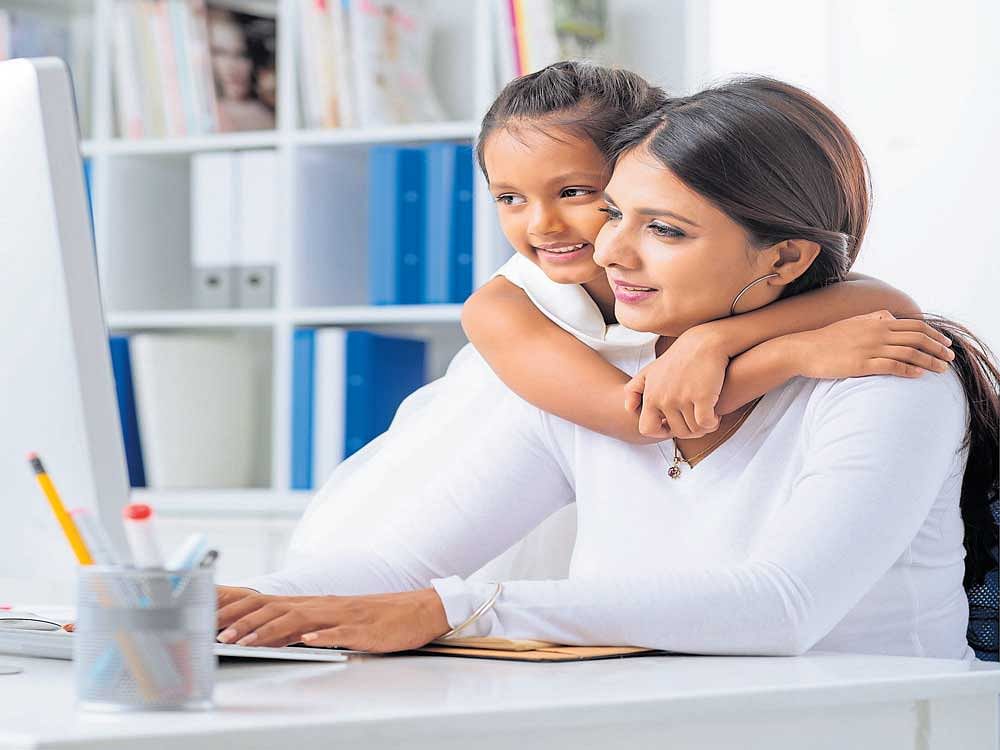 Mother working at home office with daughter on her lap