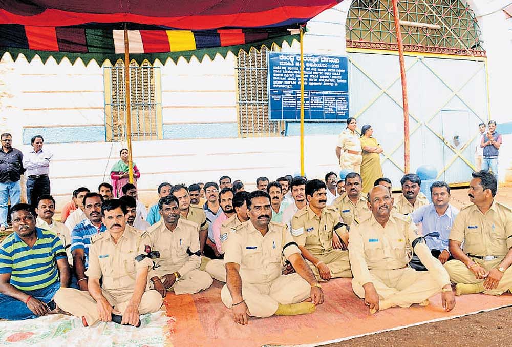Members of the staff stage a sit-in protest in front of the central prison at Hindalga in Belagavi on Thursday. DH photo