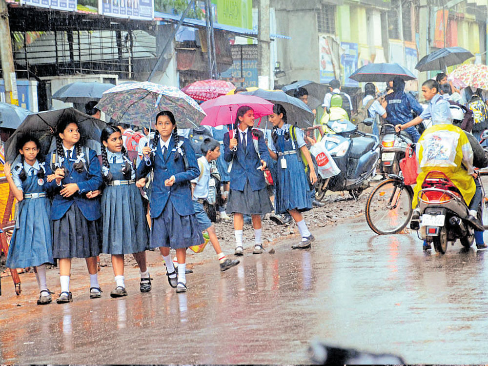 Children walk with umbrellas in Belagavi as the city received mild showers on Friday.