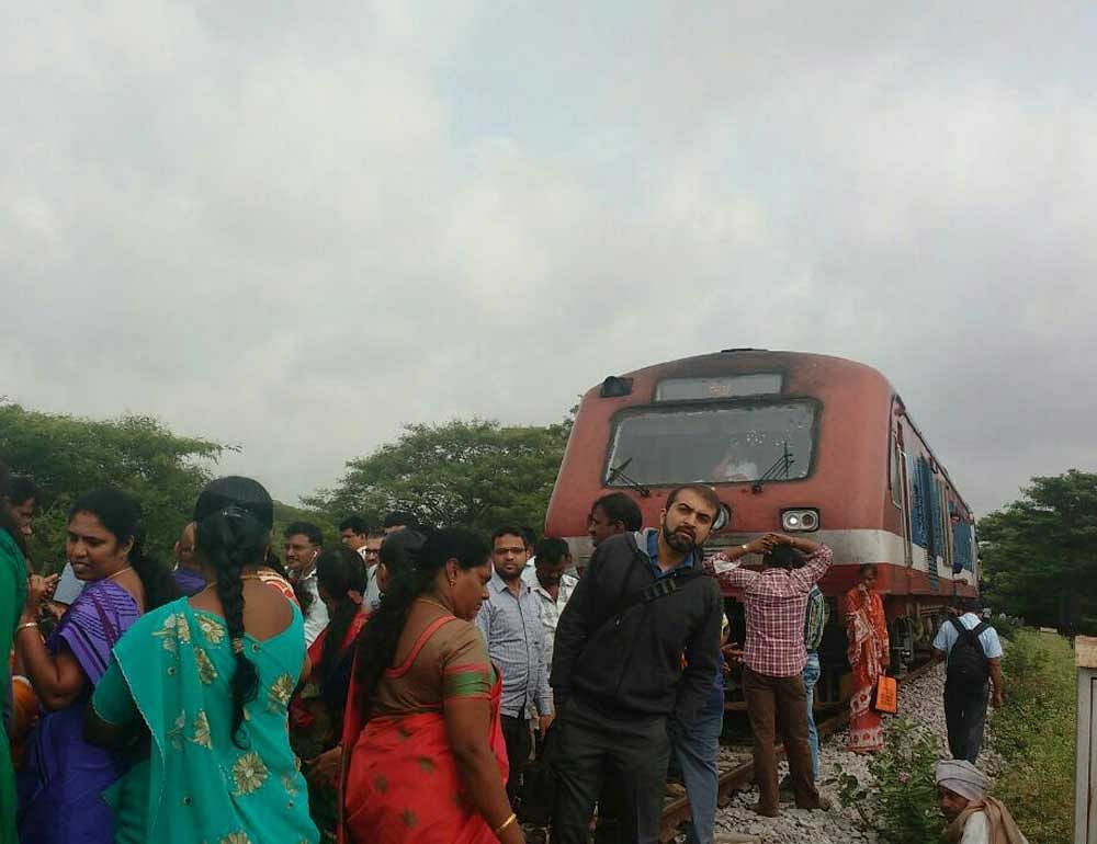 Commuters protest in front of the DEMU train at Baiyappanahalli 'A' Cabin halt station on Monday. DH PHOTO