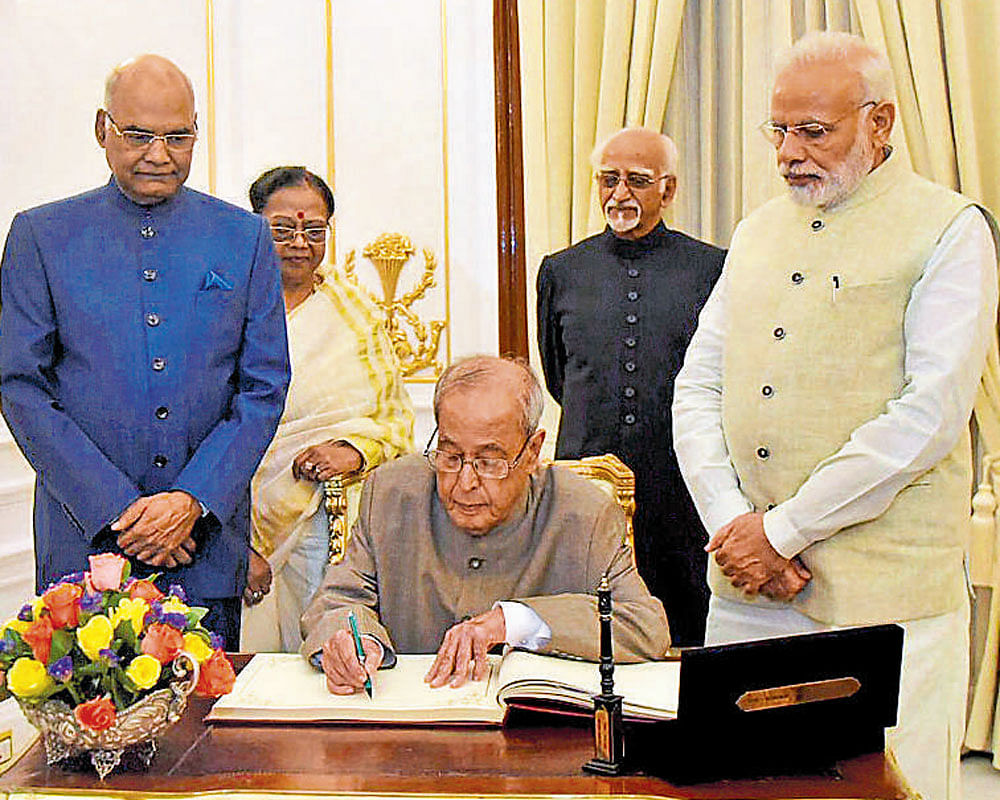 President Pranab Mukherjee signs the visitors' book at  Hyderabad House, New Delhi, during his farewell dinner hosted by Prime Minister Narendra Modi on Saturday.  President-elect Ram Nath Kovind and Vice President Hamid Ansari looks on. PTI