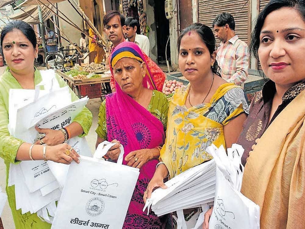 Members of Leaders Agra distribute paper bags.
