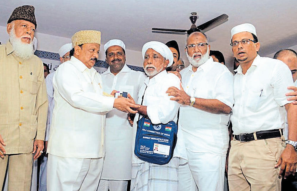 Minister for Urban Development and Haj R Roshan Baig (2nd left) hands over passport to a Haj pilgrim at Ansar PU&#8200;College on the outskirts of Mangaluru on Monday.