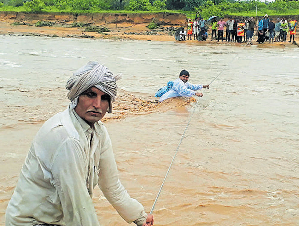 Men attempt to cross floodwaters in Deesa municipality in northern Gujarat. PTI & AFP