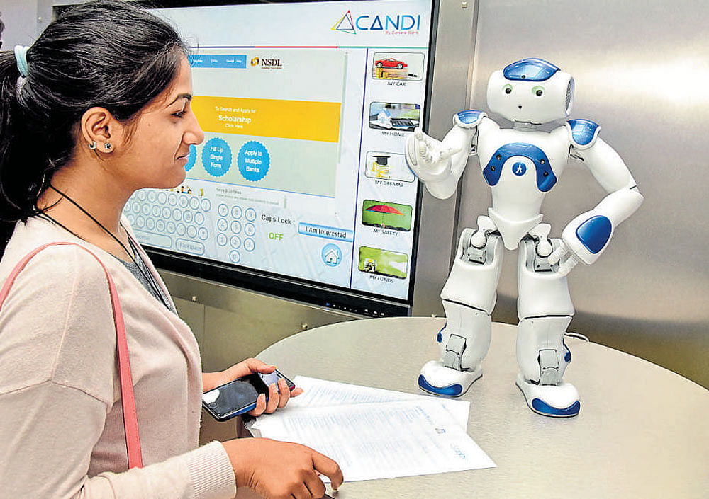 A girl collects information from a robot at Canara Bank's new digital banking branch on MG Road in Bengaluru on  Thursday. DH Photo/ S K Dinesh