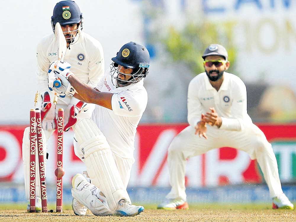 crucial blow: Sri Lankan batsman Dimuth Karunaratne has his stumps rattled by Ravichandran Ashwin. REUTERS