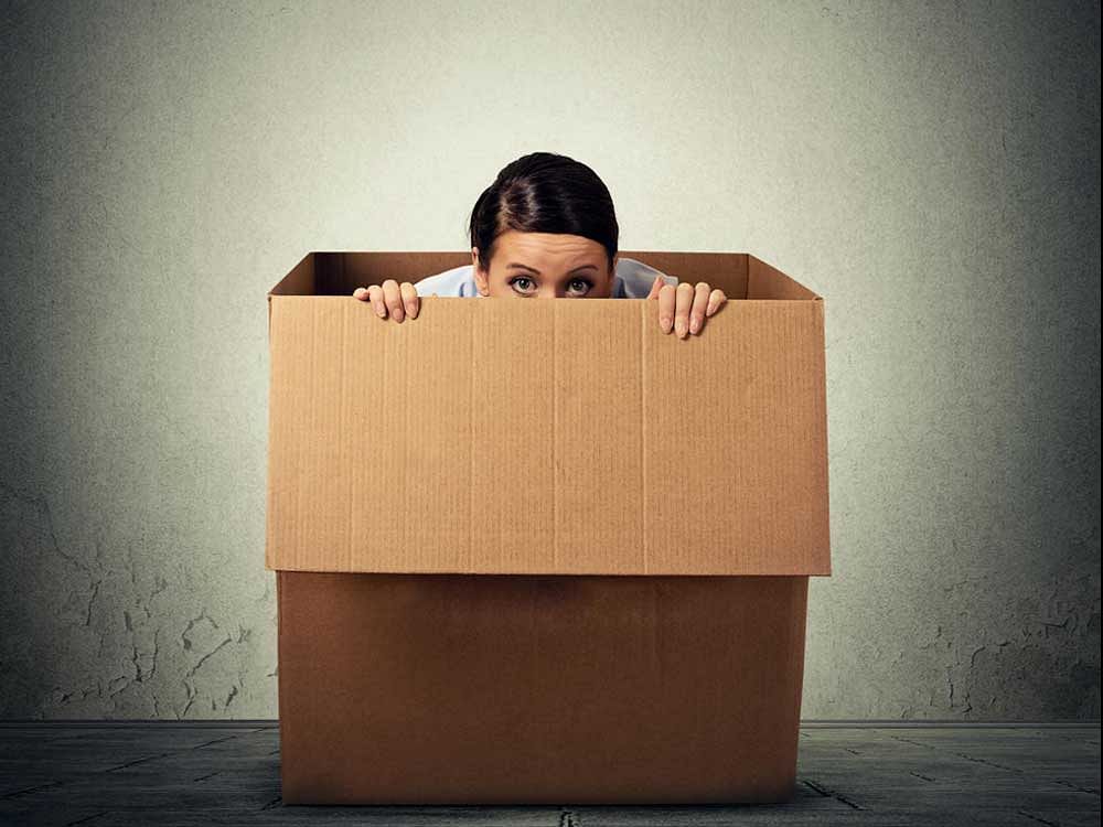 Young woman hiding in a carton box.