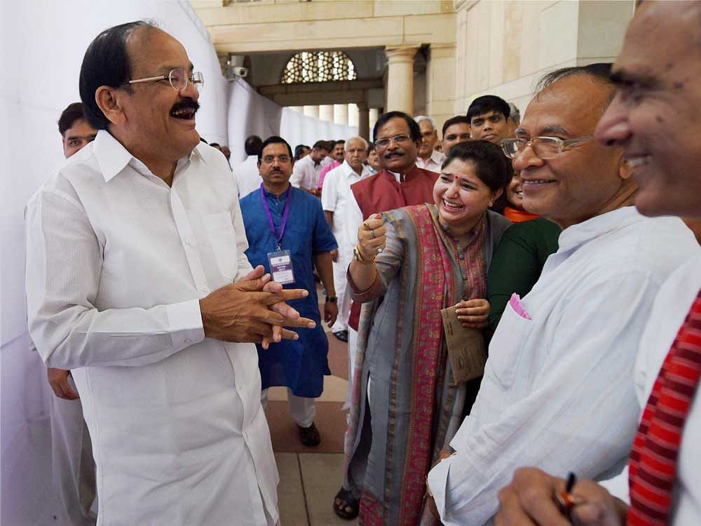 NDA candidate for Vice President Venkaiah Naidu, sharing a light moment with other MPs as he arrives to cast his vote in the Vice Presidential Election, in New Delhi on Saturday. PTI Photo