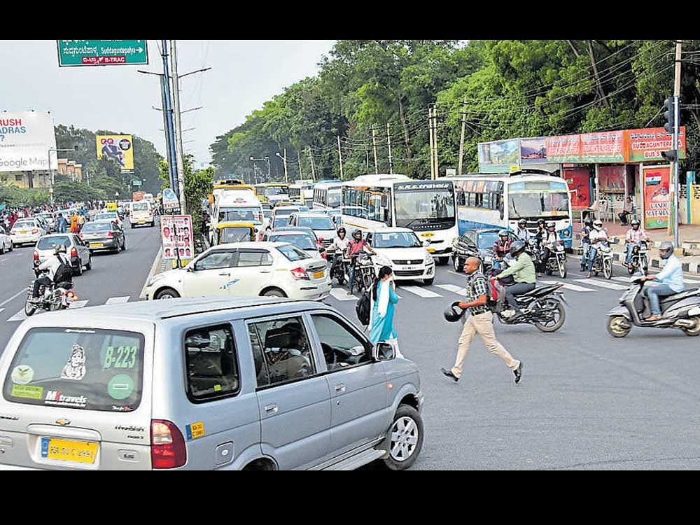 Pedestrians struggle to cross the road at Baiyappanahalli Metro Station traffic signal, in Bengaluru on Tuesday.