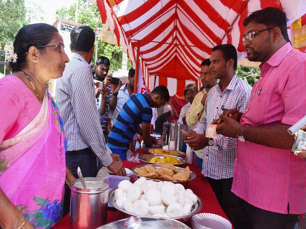 DYFI activists buy food at 'Indira Canteen' a temporary facility opened outside deputy commissioner's office in Mangaluru on Wednesday, demanding the government to extend the canteens outside Bengaluru. DH photo