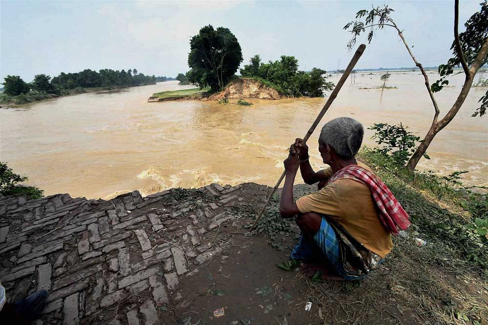 An elderly person sitting on a washed away road at flood-hit Runni Saidpur in Sitamarhi district. 98 people have died so far in a massive flood in Bihar. PTI photo.