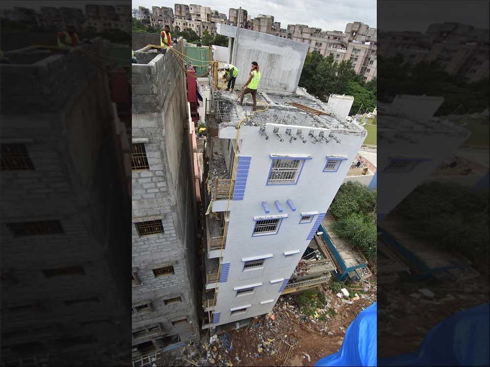 Laborers demolishing the five-storey building which began to lean at Ejipura in Bengaluru on Thursday. DH Photo by Janardhan B K
