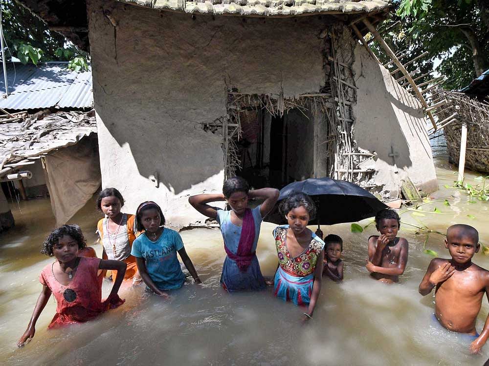 Children stand waist-deep in flood water as they wait for rescue workers in Katihar on Saturday. PTI Photo