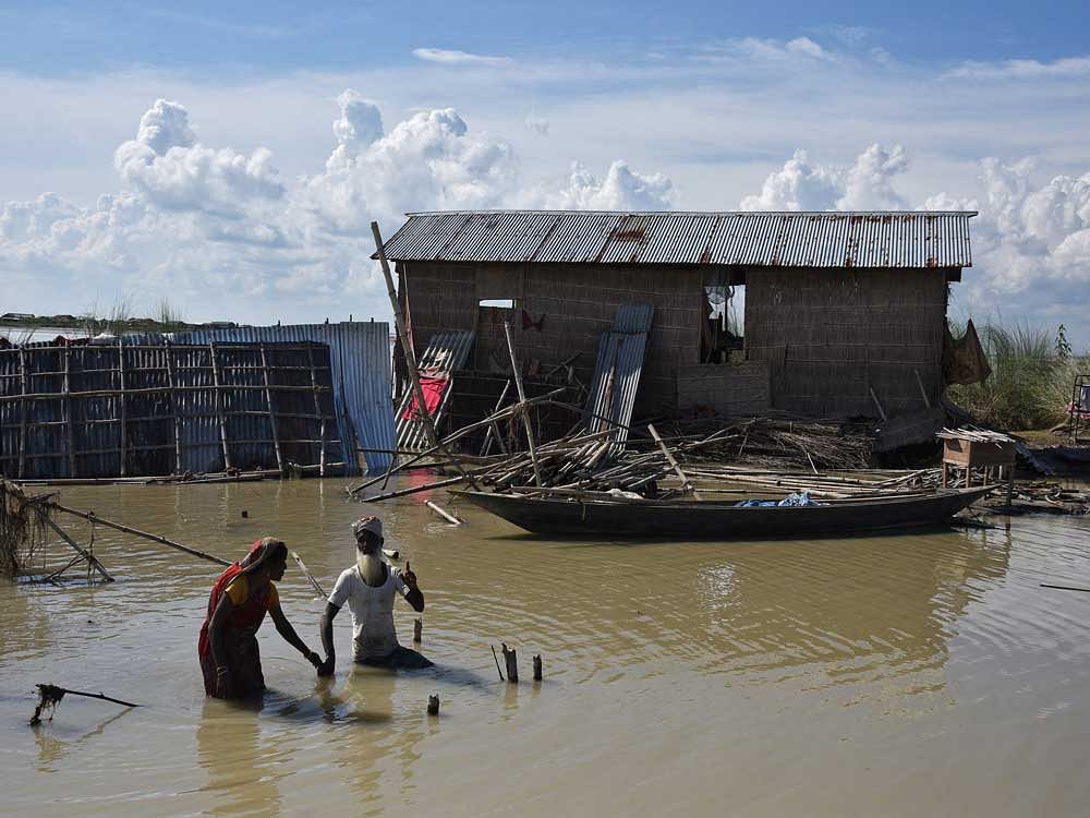 People wade through flooded waters at a village in Morigaon district in the northeastern state of Assam. Reuters Photo