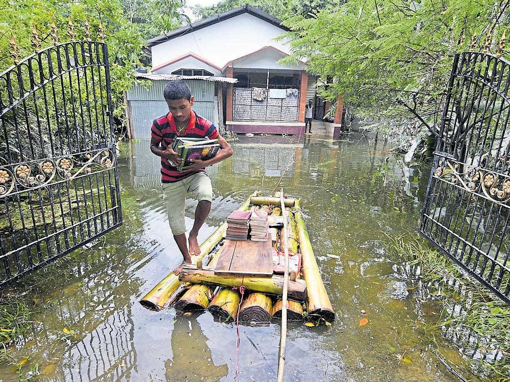 A boy uses a banana raft to transport his books in Jakhalabandha area in Nagaon district of Assam